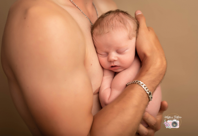 bébé dans les bras de papa en peau a peau possible au studio pendant la séance 
