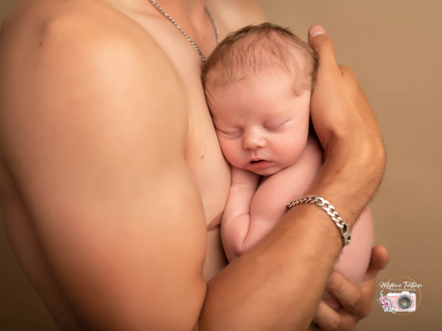 bébé dans les bras de papa en peau a peau possible au studio pendant la séance 